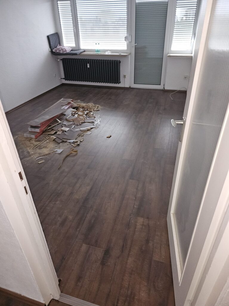 Leerer Raum mit Holzboden und Bauschutt während der Sanierung einer Wohnung in Nürnberg